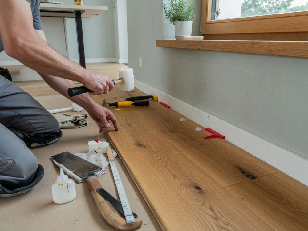 Bodenleger passt eine Diele passgenau an die Wand an